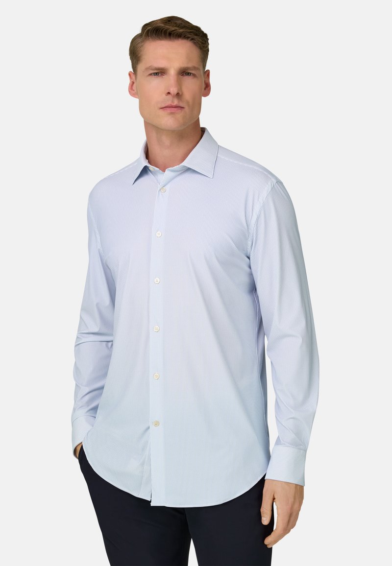 Chemise habillée bleu clair à fines rayures blanches, manches longues, col boutonné et ourlet arrondi. Présente des boutons blancs et une texture lisse.
