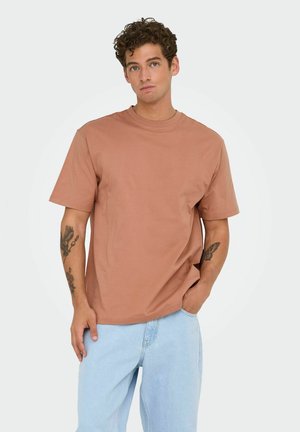 Klei-kleurig katoen t-shirt met een relaxed fit, korte mouwen en een ronde hals, gecombineerd met lichtblauwe denim jeans.
