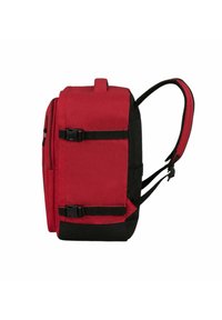 Punainen ja musta reppu, jossa säädettävät olkahihnat, valmistettu kankaasta. Varustettu kahdella soljella, etutaskun vetoketjulla ja yläkahvalla. Kompakti muoto.