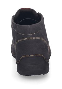 Bottine en cuir noir avec des coutures jaunes contrastantes, des détails de coutures courbes, un col rembourré et une semelle en caoutchouc texturé.