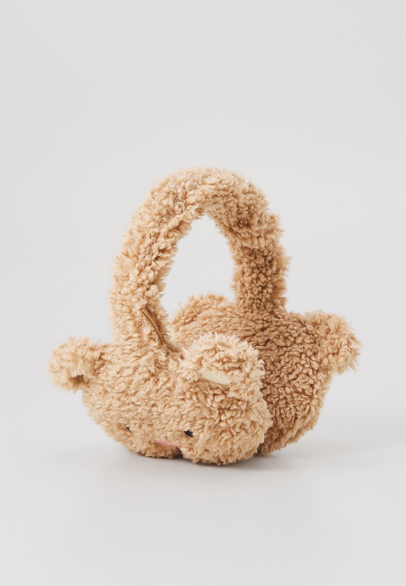 Puha, plüss maci alakú táska világos bézs színben, bolyhos textúrával, kerek fogantyúval és kis füllel, hímzett arcvonásokkal.