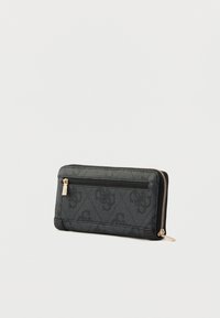 Fekete, cipzáras pénztárca, dombornyomott mintával, sima részletekkel és aranyszínű cipzárhúzóval, amelyhez egy kis címke van csatolva.