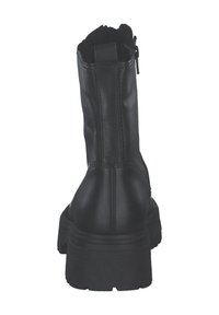 Zwarte leren enkelboot met een gestructureerde zool, verticale stikdetails en een zijrits voor gemakkelijk aan- en uittrekken.
