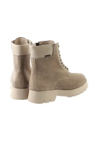 Para beżowych zamszowych botków do kostki z grubymi gumowymi podeszwami, sznurowanym przodem, wysokimi wyścielanymi kołnierzami i małą metką Gore-Tex z boku.