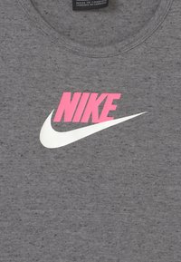 Nike sivi majica s okruglim izrezom od mješavine pamuka, s velikim ružičastim logotipom "NIKE" i bijelim swoosh-om. Glatka tekstura s mramornim uzorkom.