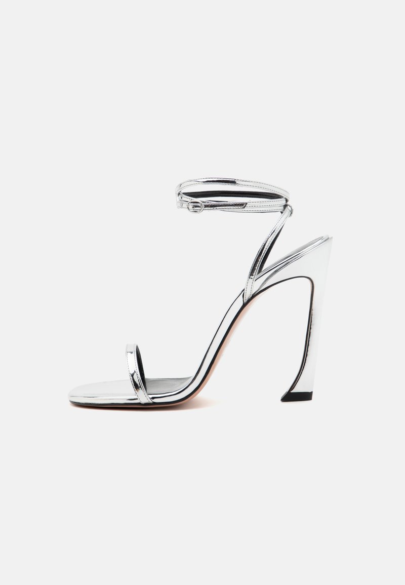 Ασημί μεταλλική ψηλή σαγιονάρα με λεπτή ανατομική λουρί, ανοιχτό μπροστινό μέρος και κομψό, καμπύλο σχέδιο τακουνιού. Απαλή υφή, ελάχιστες λεπτομέρειες.