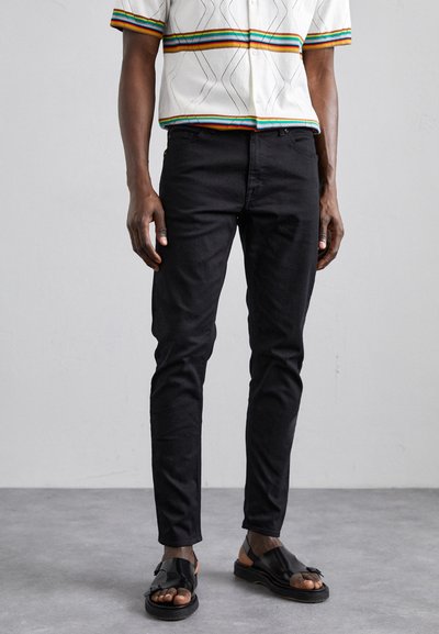 Czarne dżinsy slim-fit wykonane z denimu, posiadające klasyczny pięciopocketowy krój. W zestawie z czarnymi sandałami i wielokolorową koszulą z krótkim rękawem.