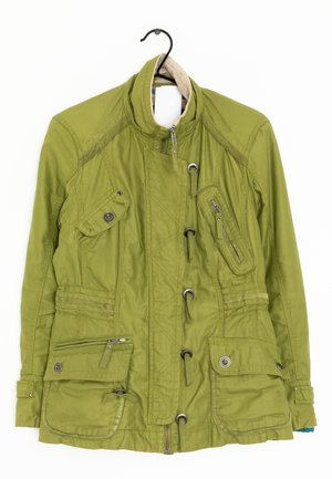 Groene utiliteitsjas met meerdere zakken met rits en knopen, ritssluiting aan de voorkant, toggledetails en een hoge kraag, hangend aan een zwarte hanger.