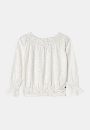 Blouse blanche à manches longues avec motif œillet, encolure smockée élastique, poignets et ourlet, et détails subtils de volants sur les manches et le bas.