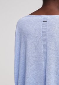 Jasnoniebieski sweter dzianinowy z szerokim dekoltem łódki oraz teksturowanym detalem szwu z tyłu, wykonany z miękkiego, lekkiego materiału.