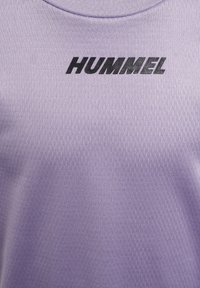 Lila idrottströja med en texturerad tygkvalitet, rund halsringning och "HUMMEL"-logotypen i svart över bröstet.