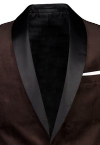Giacca da smoking in suede marrone con colletto a scialle in raso nero, caratterizzata da una texture liscia e una tasca con un bordo bianco.