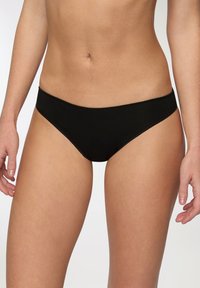 Slip bikini neri con texture liscia, design a vita bassa e un semplice elastico in vita. Cuciture minime e senza modelli o accessori.