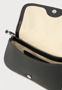 Zwarte lederen tas met textuur, klep open, beige stoffen interieur en zilveren magnetische sluiting, met een klein binnenvak zichtbaar.