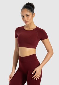 Bordeaux atletisk crop top med korte ærmer og ribbet kant, parret med højtaljede leggings i matchende farve, der har en glat, strækbar kvalitet.