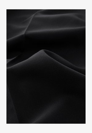 Črna tkanina z gladko teksturo, ki ima subtilne nagube in mehke zvitke, z mat zaključkom in lahkotno kakovostjo.