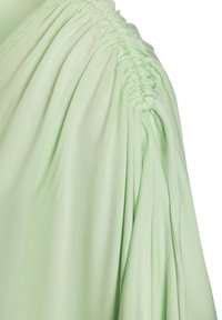 Hellgrünes Oberteil mit gerafften Details an der Schulter, aus weichem Stoff gefertigt, mit lässigem Schnitt und fließender Textur.