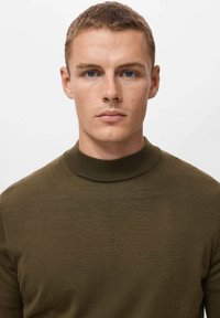 Olivno zelena pletena džemper s visokim ovratnikom, prilagođenim dizajnom i glatkom teksturom, prikladan za ležerno nošenje.