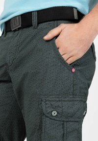 Cargo-Hosen in Dunkelgrau mit einem strukturierten Rautenmuster. Verfügt über schräg geschnittene Taschen, einen roten Akzentknopf und einen schwarzen gewebten Gürtel.