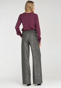 Bordowy longsleeve z luźnym krojem, połączony z szarymi spodniami o wysokim stanie i szerokich nogawkach, posiadającymi teksturowany wzór i elastyczny pas.