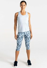 Helles blaues ärmelloses Sportoberteil kombiniert mit blauen Capri-Leggings im Schlangenmuster und schwarzen Sportschuhen. Glattes Material mit lockerer Passform.