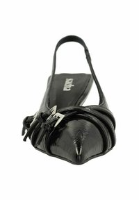 Chaussure plate en cuir noir avec un bout pointu, arborant un design de lanière twistée et des accents en métal argenté. Texture lisse sur l'ensemble.