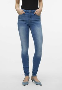 Visoke skinny traperice svijetloplave boje s izblijedjelim pranjem, imaju prednje džepove, zatvaranje na gumb i uski kroj.