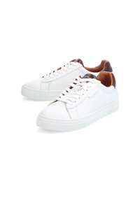 Baskets blanches en cuir avec une semelle plate, un bout rond et un design à lacets. Accent marron au talon, avec une texture lisse.