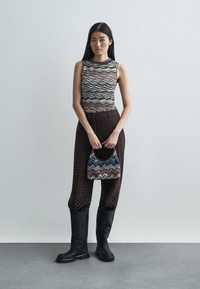 Patterned knit top with wavy stripes in brown, orange, and white; brown wide-leg patterned pants; black knee-high boots; multicolored handbag.