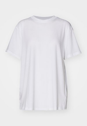 Camiseta oversized branca feita de algodão, com decote redondo, mangas curtas e rachas laterais para um ajuste descontraído. Textura suave.