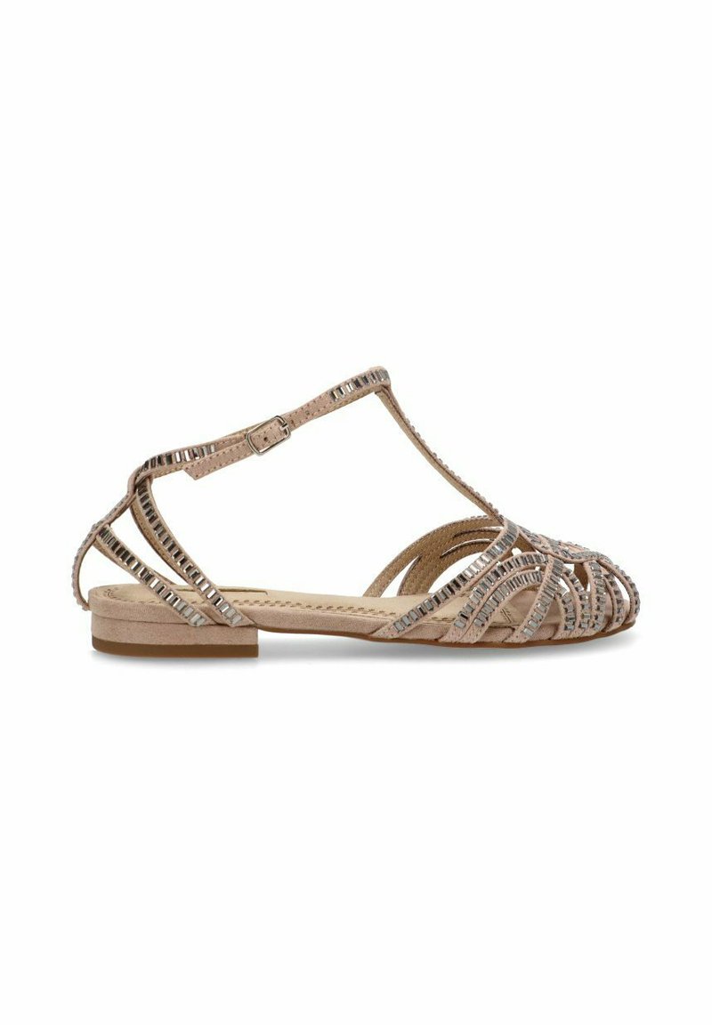 Sandalias planas beige con un diseño de tiras y detalles metálicos. El zapato tiene una punta redondeada y una suela acolchada.