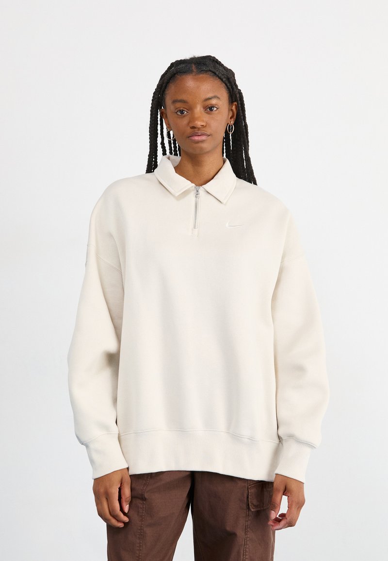 Ανοιχτό μπεζ φούτερ με μισό φερμουάρ στον γιακά, που διαθέτει ένα μικρό λευκό λογότυπο στο στήθος. Φτιαγμένο από μαλακό ύφασμα με άνετη εφαρμογή.