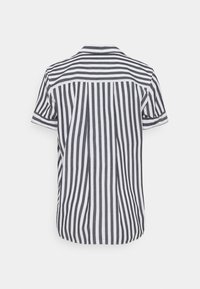 Camicia a maniche corte con bottoni, caratterizzata da strisce verticali bianche e nere sulla schiena e strisce orizzontali sulla parte superiore della schiena e sulle maniche.
