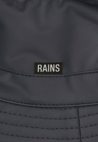 Black waterproof bucket hat with a smooth, matte texture; features the label "RAINS" in white on a black background.