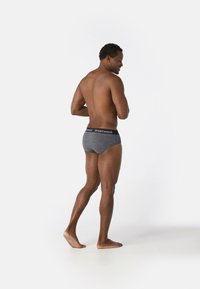Sous-vêtements en laine grise pour homme avec une ceinture élastique noire portant le logo "Smartwool", conçus pour le confort et l'ajustement.