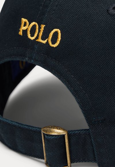 Nahaufnahme einer schwarzen Stoffkappe mit goldener "POLO"-Stickerei und verstellbarem Messingschnallenriemen an der Rückseite.