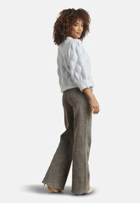 Light blue knitted pullover with diamond pattern, three-quarter sleeves; paired with high-waisted grey flared jeans and nude heels.