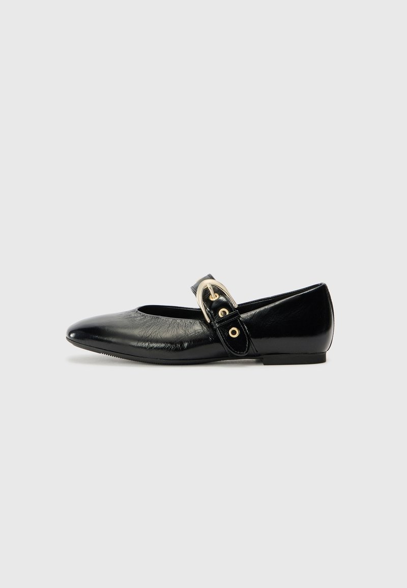 Chaussure plate Mary Jane noire à bout pointu avec finition brillante et bride à boucle dorée sur fond gris.