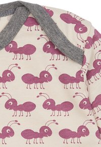 Baumwollbody mit einem beigen Hintergrund, auf dem lila Ameisenmuster wiederholt sind. Der Kragen und die Einfassung sind grau und haben eine sanfte Textur.