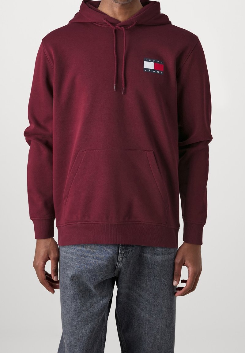 Felpa color bordeaux con un patch logo che presenta rettangoli rossi, bianchi e blu. Tessuto morbido, maniche lunghe e tasca a marsupio frontale.