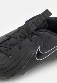 Fekete szintetikus focicipő texturált felsőrésszel, összehangolt fűzőkkel és fehér Nike logóval. A teljesítmény érdekében kialakított, letisztult dizájnnal.