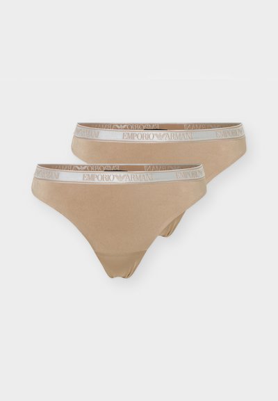 Δύο μπεζ εσώρουχα τύπου στρινγκ με λευκές ελαστικές μέσης που φέρουν το λογότυπο Emporio Armani και το σύμβολο αετού.