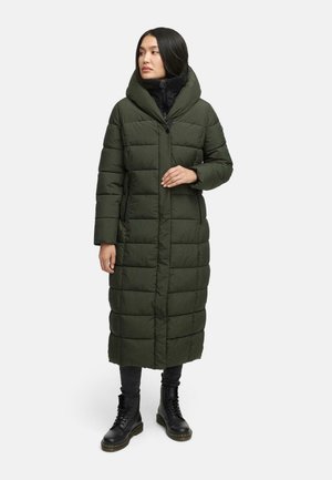 Long, olive green puffer coat with a hood, featuring quilted sections, front zip closure, and side pockets. Worn over black outfit and boots.