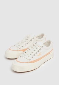 Zapatillas de lona blancas con acentos melocotón, puntera redonda y suela de goma. Presentan ojetes de metal y cordones lisos. Logo en el lateral.