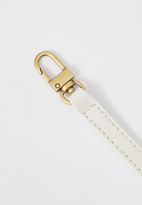 Witte leren riem met gouden metalen sluiting en draaibeugel. Stikdetails zichtbaar langs de rand van de riem.