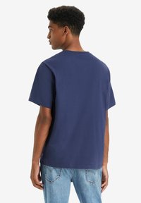 Marineblauwe katoenen t-shirt met een relaxte fit, ronde hals en korte mouwen, gecombineerd met lichtblauwe spijkerbroek.