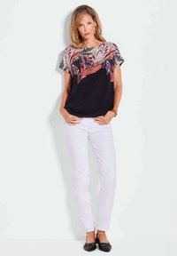 Zwarte top met kleurrijke veren- en bloemenprint, korte mouwen, gecombineerd met witte slim-fit broek en zwarte ballerina's. Gladde stof, casual ontwerp.