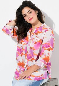 Camisa de manga larga de botones en tejido transparente, con un patrón de acuarela en tonos rosa, naranja y blanco. Incluye un bolsillo en el pecho y mangas dobladas.