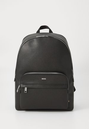 Sac à dos noir avec une surface lisse et texturée, doté d'une poche zippée à l'avant et du nom de la marque "BOSS" en relief sur la poche inférieure.