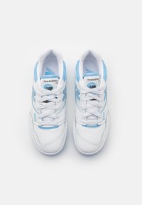 White athletic shoes with light blue accents, featuring a smooth leather upper, laces, padded collar, and subtle logo details.